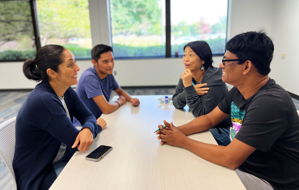 four people sitting at table talking